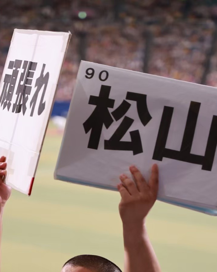 「頑張れ」「90 松山」のボードを両手で掲げる団員