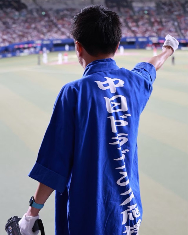 拡声器を持ち、腕を上げて応援を指揮する団員の後ろ姿